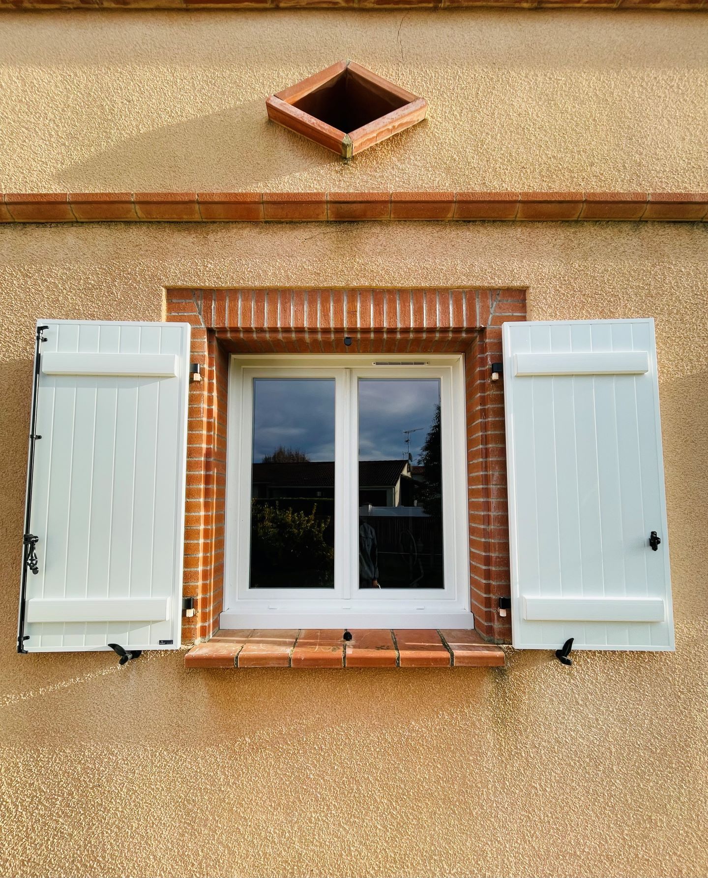 Fenêtre avec un cadre en briques et des volets à battants