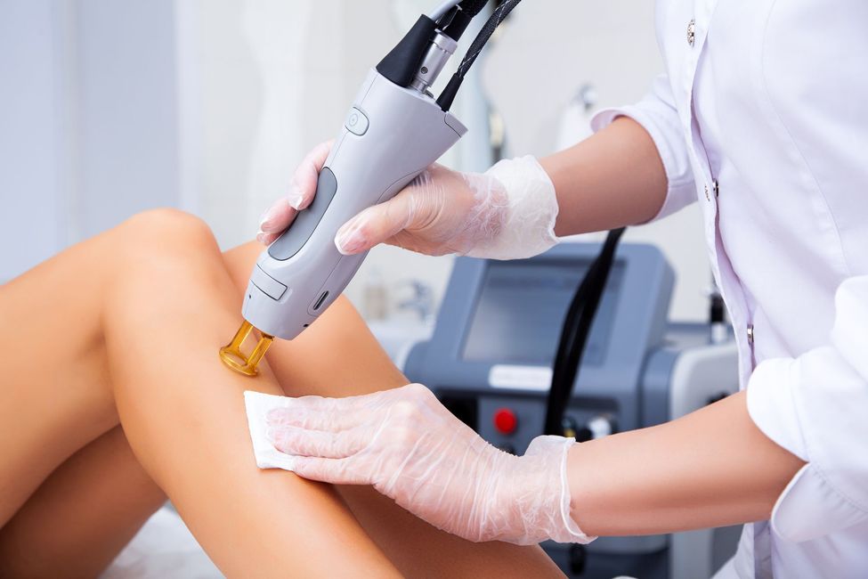 Une praticienne épilant les jambes d'une femme au laser.