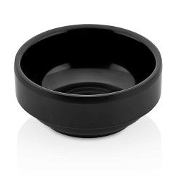 Cuenco de cerámica negro y redondo sobre una superficie blanca.