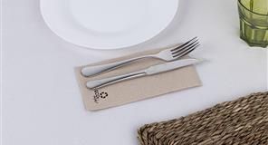 Tenedor y cuchillo sobre una servilleta beige, colocados junto a un plato blanco y un mantel individual tejido.