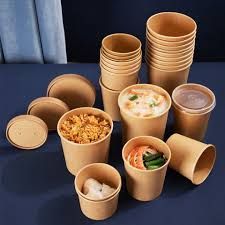 Recipientes de papel marrón para alimentos, algunos con comida en su interior, apilados sobre una superficie azul.