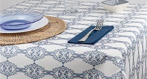 Mesa puesta para cenar con mantel estampado, platos azules y cubiertos.
