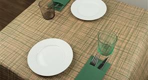 Mesa puesta para dos: platos blancos, servilletas verdes con cubiertos y dos vasos.