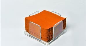 Servilletas cuadradas de color naranja en un soporte de acrílico transparente sobre una superficie blanca.