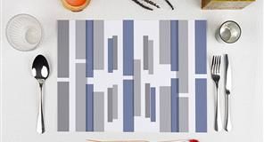 Juego de mesa con cuchara, tenedor, cuchillo y mantel estampado en tonos grises y azules.