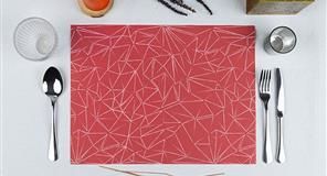 Puesta de mesa: mantel geométrico rojo con cubiertos, vasos y pequeños elementos decorativos.