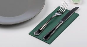 Tenedor y cuchillo sobre una servilleta verde junto a un plato gris.