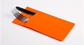 Servilleta naranja sosteniendo un tenedor y un cuchillo sobre una superficie blanca.