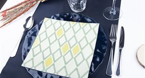 Cubierto con servilleta estampada, cubiertos y plato azul.