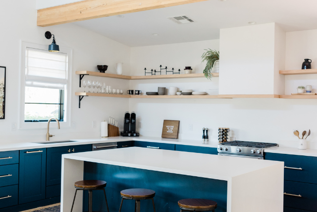 Une cuisine avec des armoires bleues, des comptoirs blancs et un grand îlot.