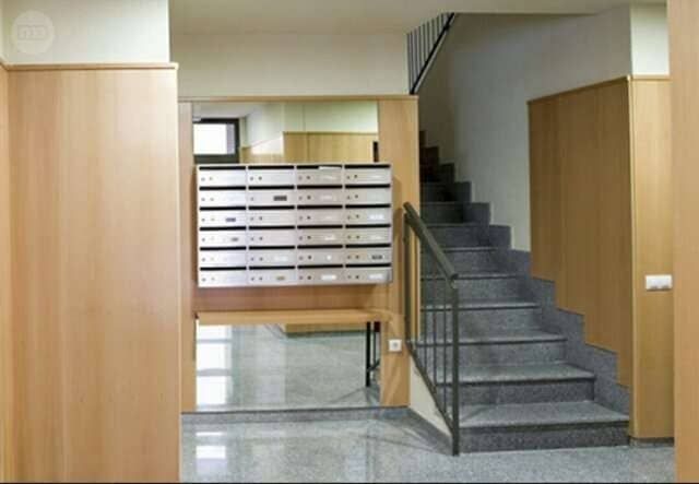 Un pasillo con escaleras y buzones en la pared.