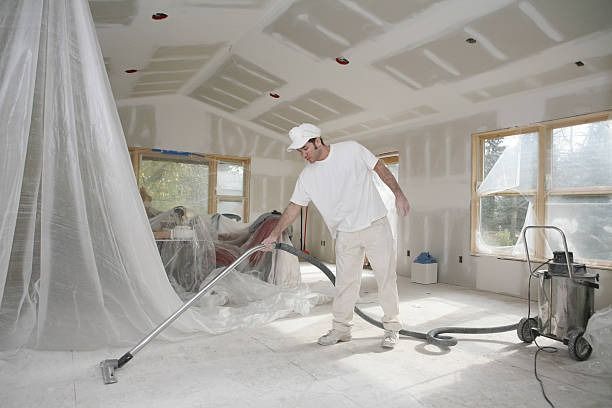 Un hombre está limpiando una habitación con una aspiradora.