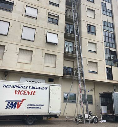 Un camión blanco está estacionado frente a un edificio con una escalera adjunta.