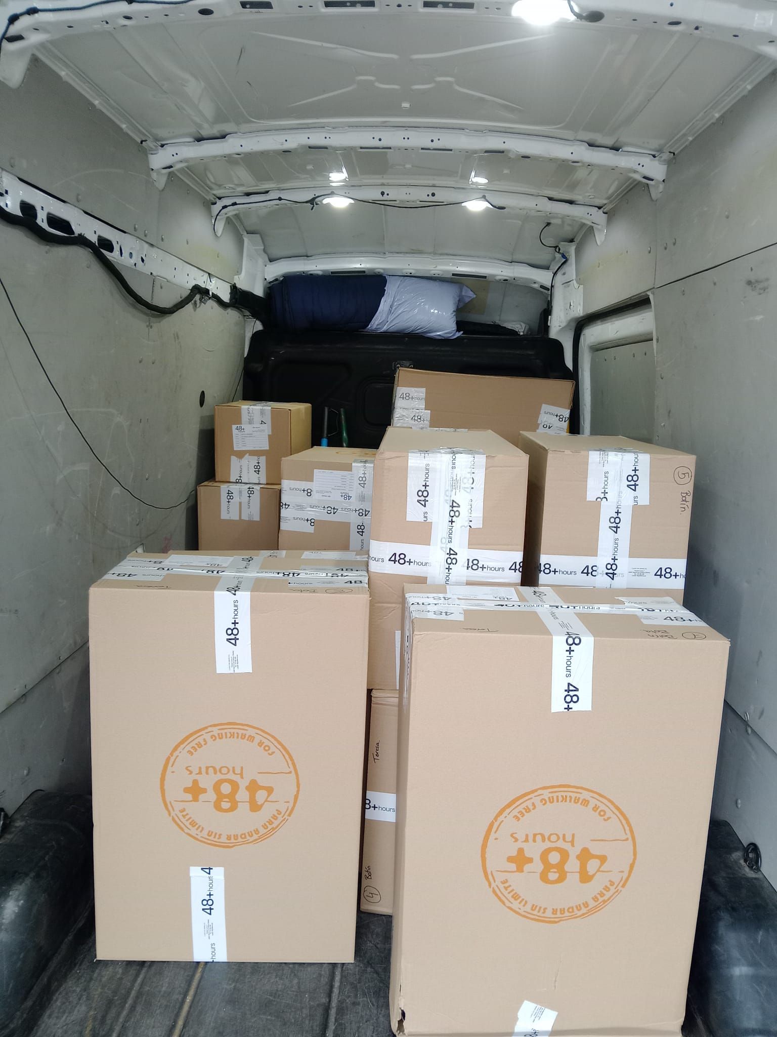 Una furgoneta blanca llena de cajas de cartón con el número 48 en ellas.