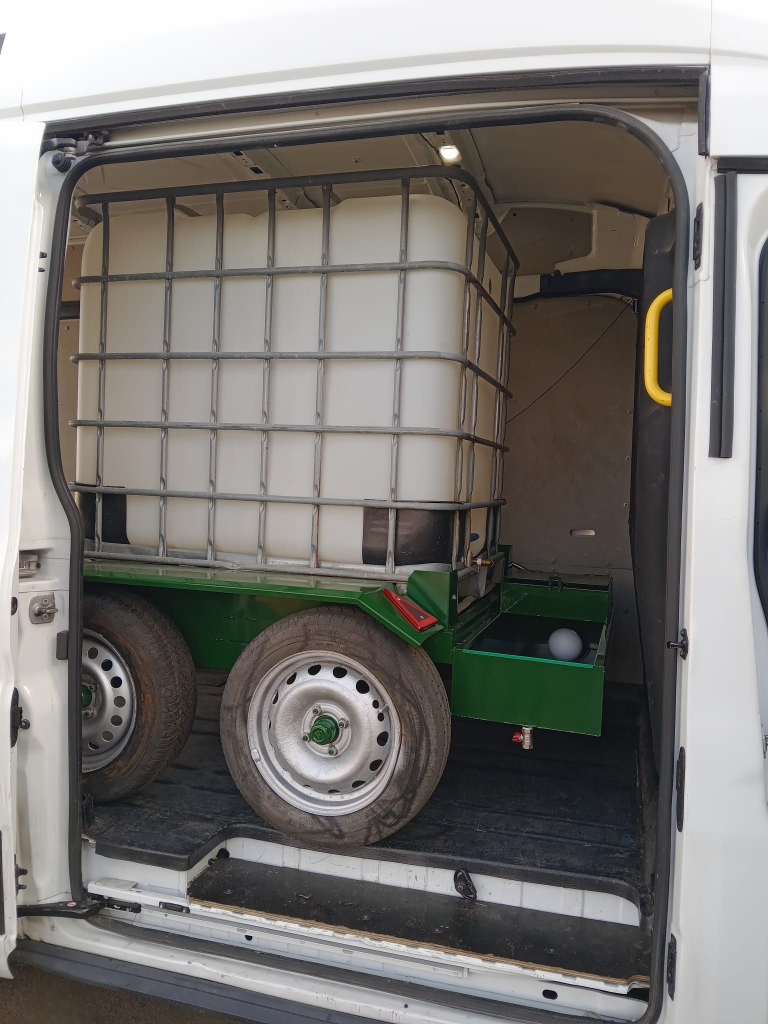 La parte trasera de una camioneta blanca con un remolque acoplado.