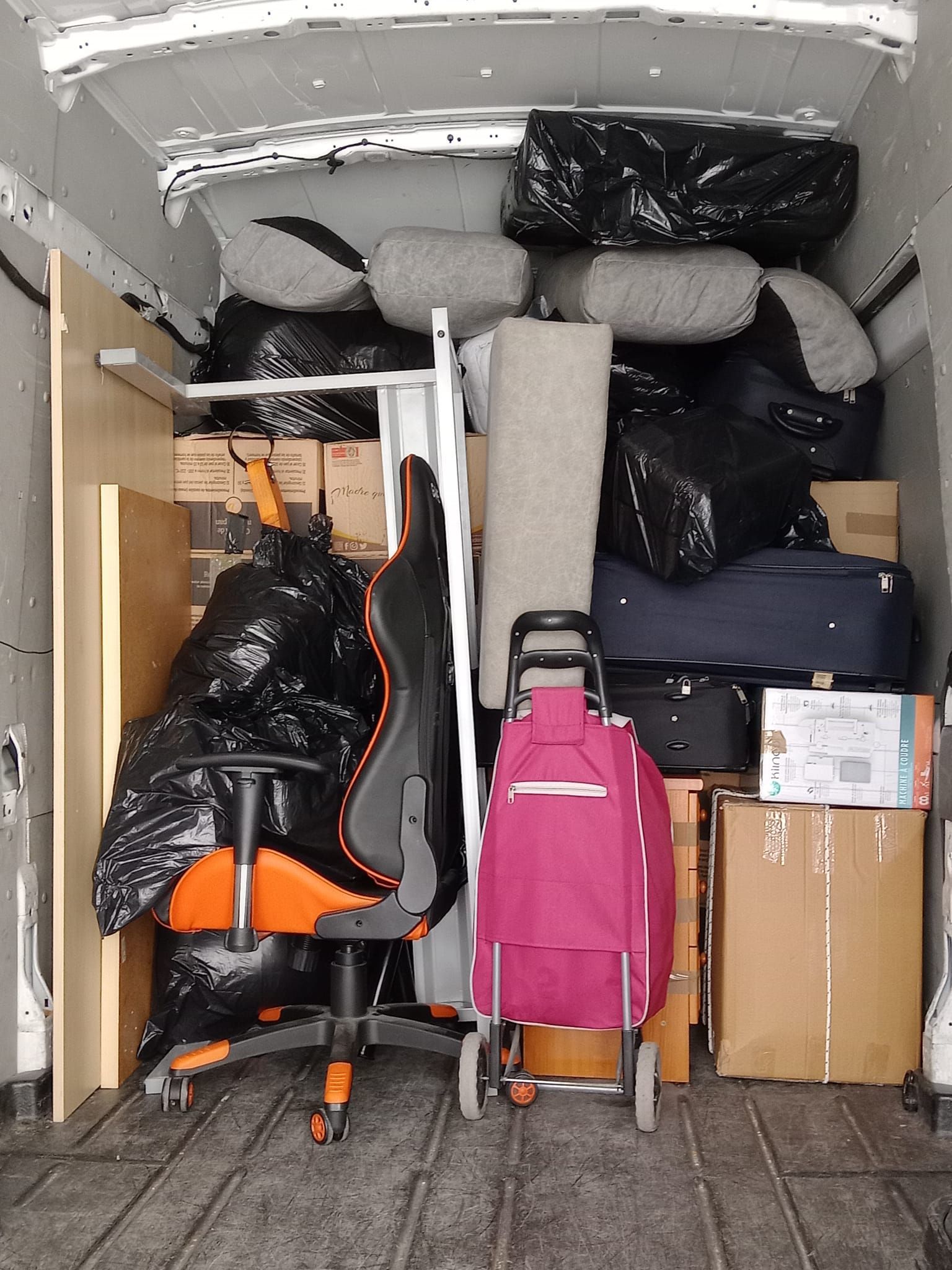 Una camioneta está llena de muchas cosas, incluida una silla y equipaje.