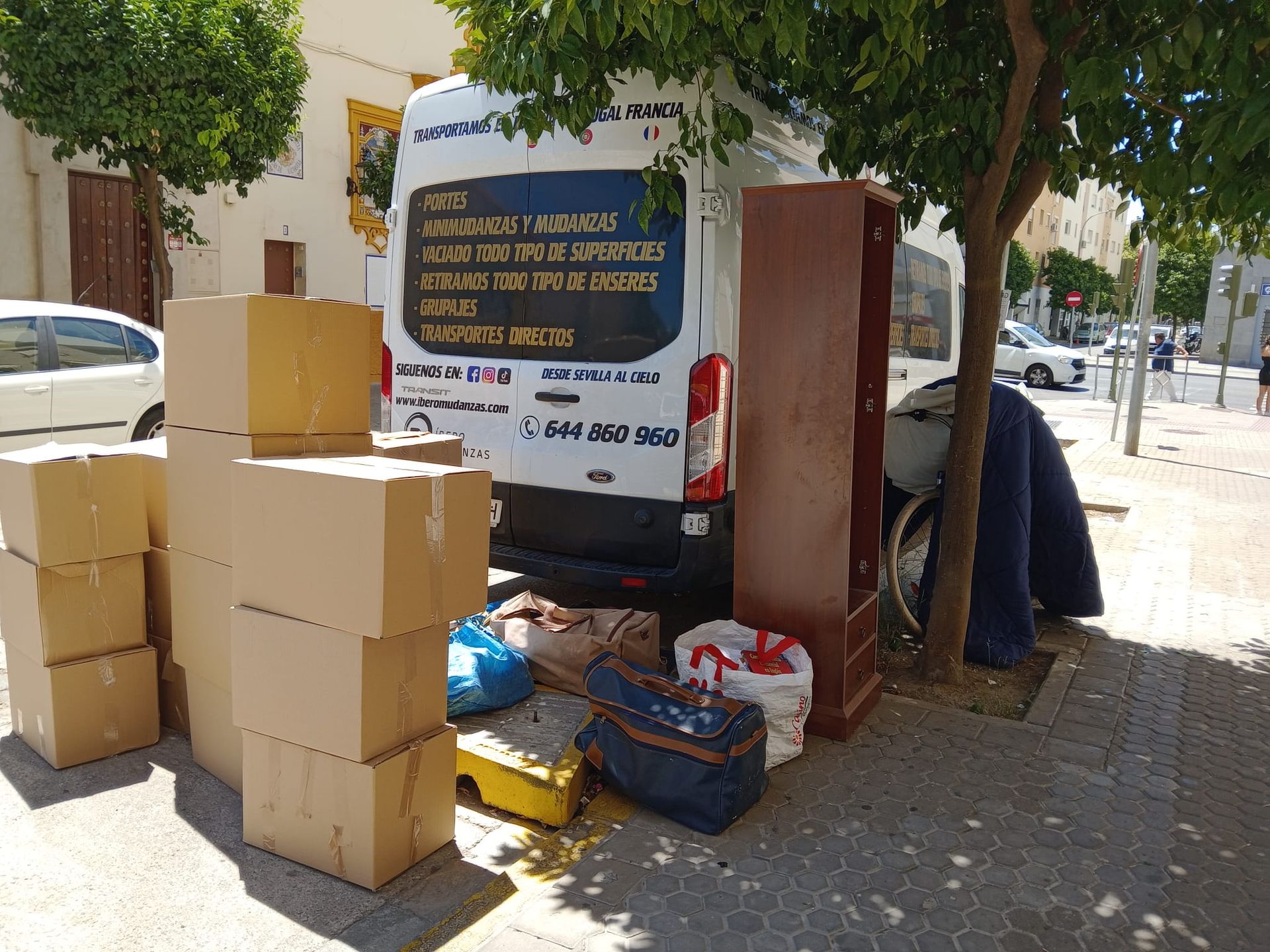 Una camioneta blanca está estacionada al costado de la carretera rodeada de cajas de cartón.