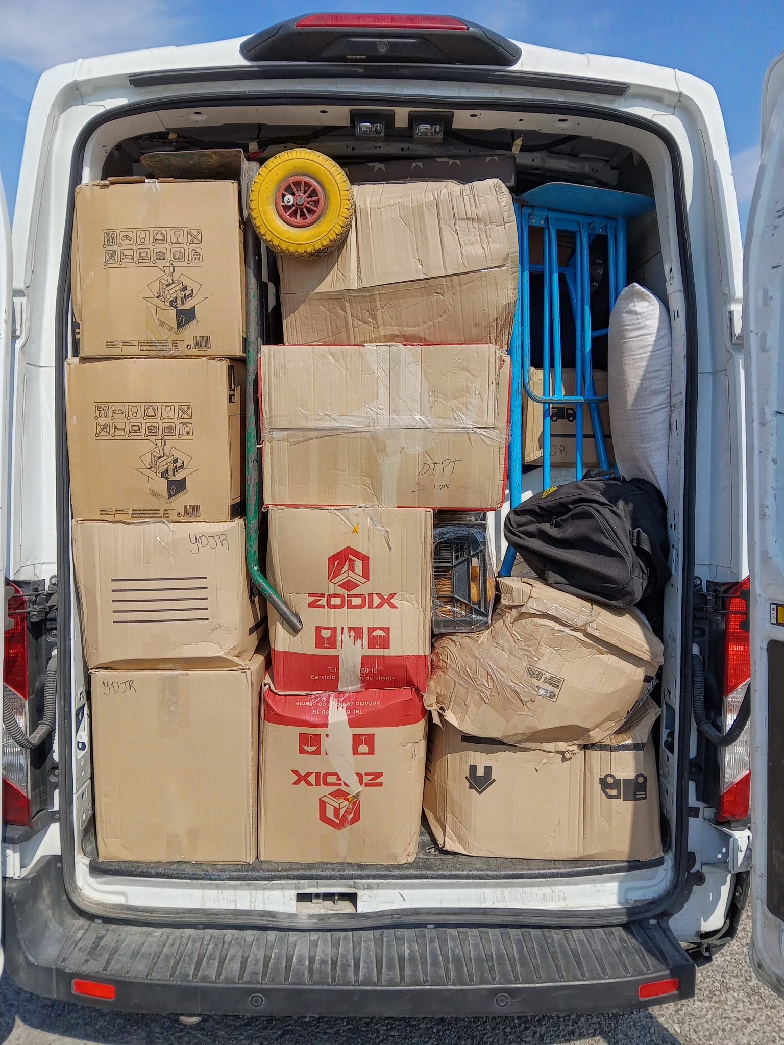 La parte trasera de una camioneta blanca está llena de cajas.