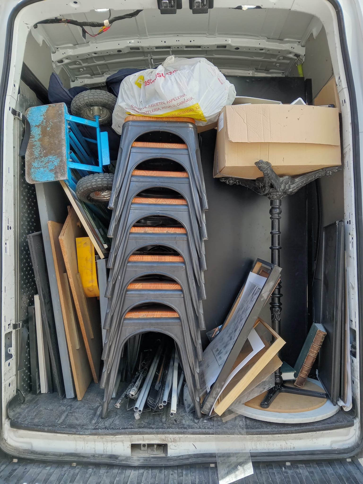 La parte trasera de una camioneta está llena de muchos muebles y cajas.