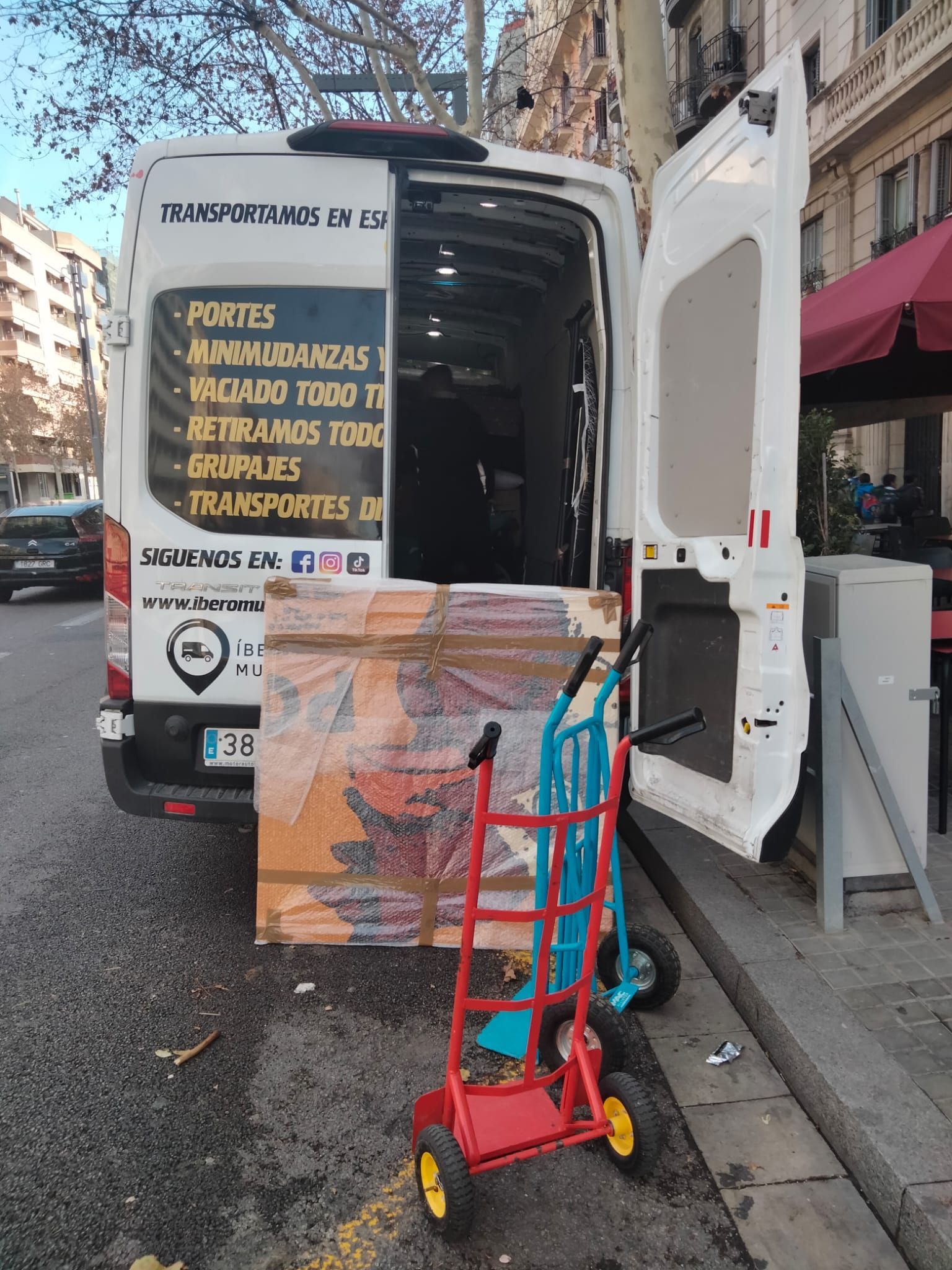 Una camioneta blanca con la puerta abierta está estacionada al costado de la carretera.