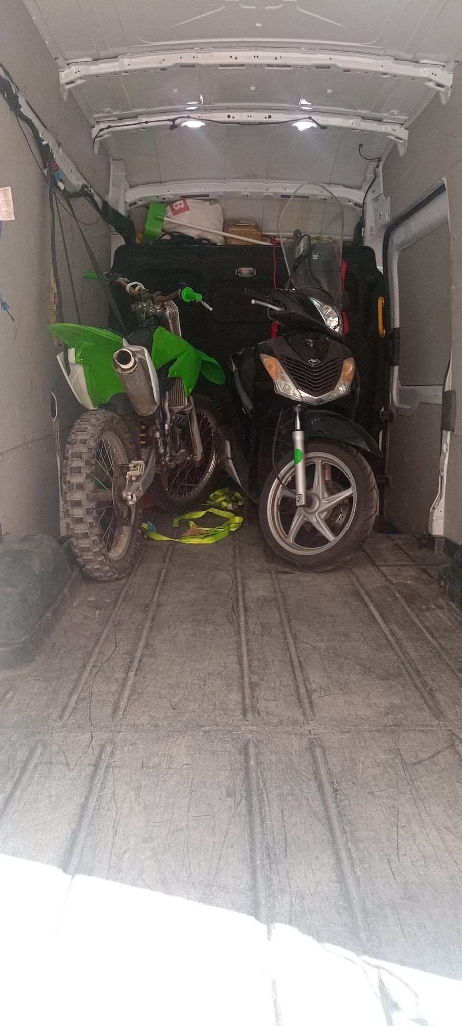 Dos motos de cross están estacionadas en la parte trasera de una camioneta.