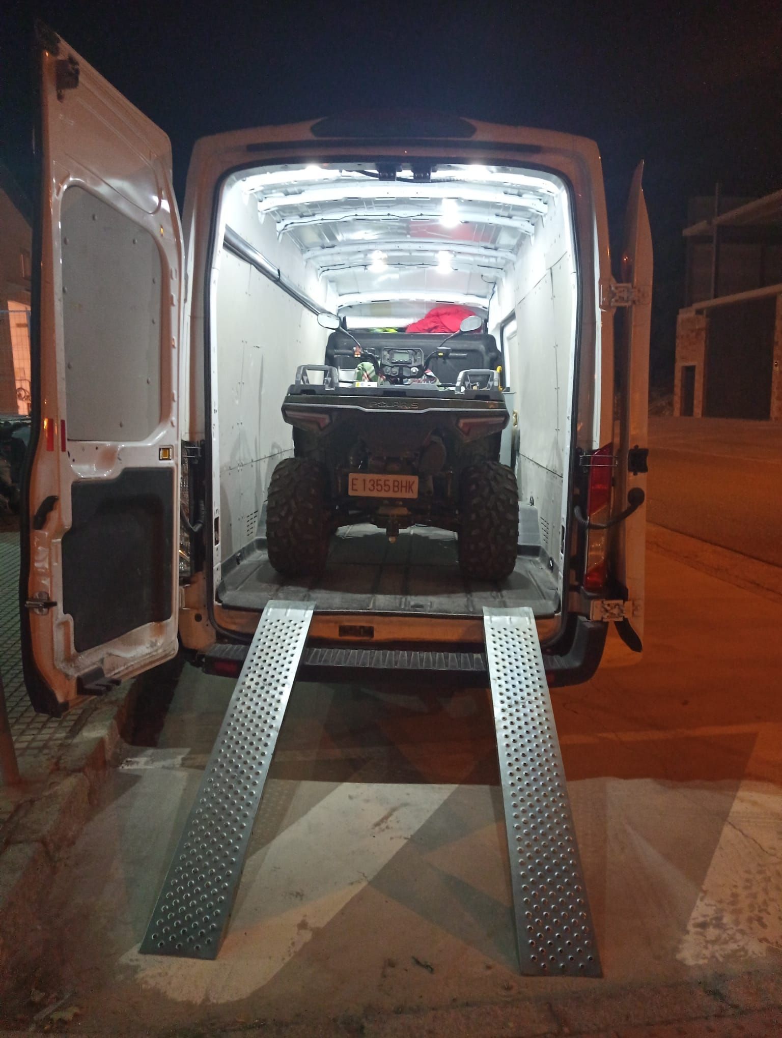 Se está cargando un vehículo en una camioneta con rampas.