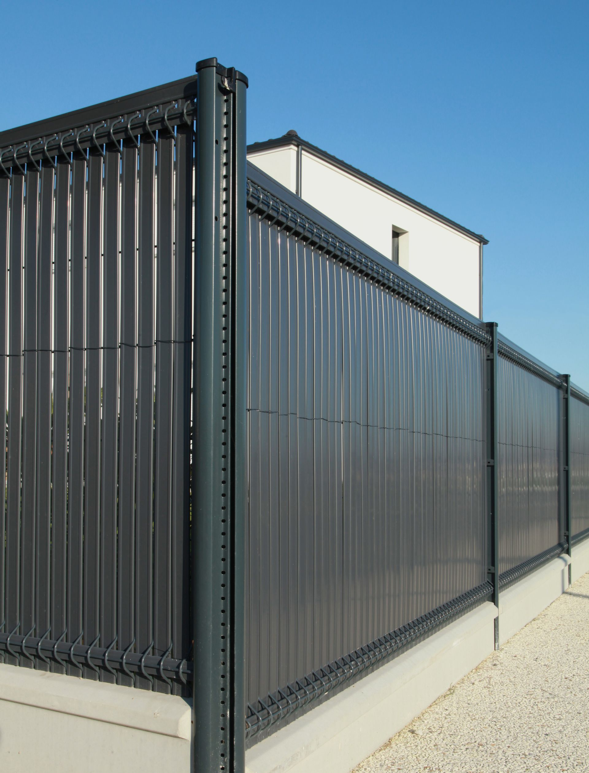 Une clôture rigide avec des brise-vue sur des soubassements.