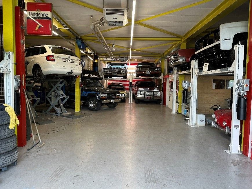 Person dokumentiert etwas an einer offenen Motorhaube