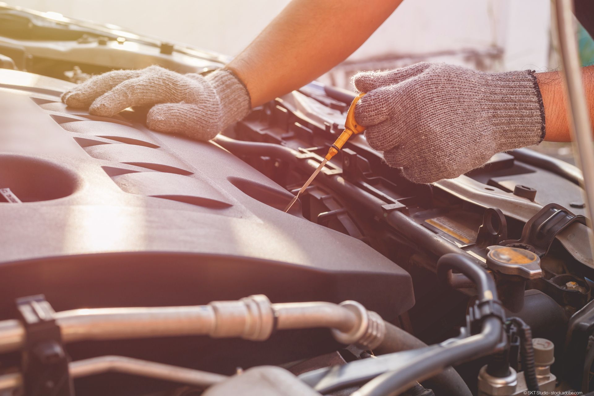 Eine Person prüft den Ölstand eines Autos mit einem Ölmessstab.