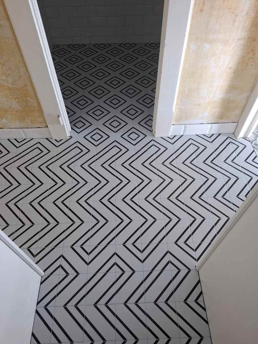Un sol en carrelage noir et blanc avec un motif géométrique.
