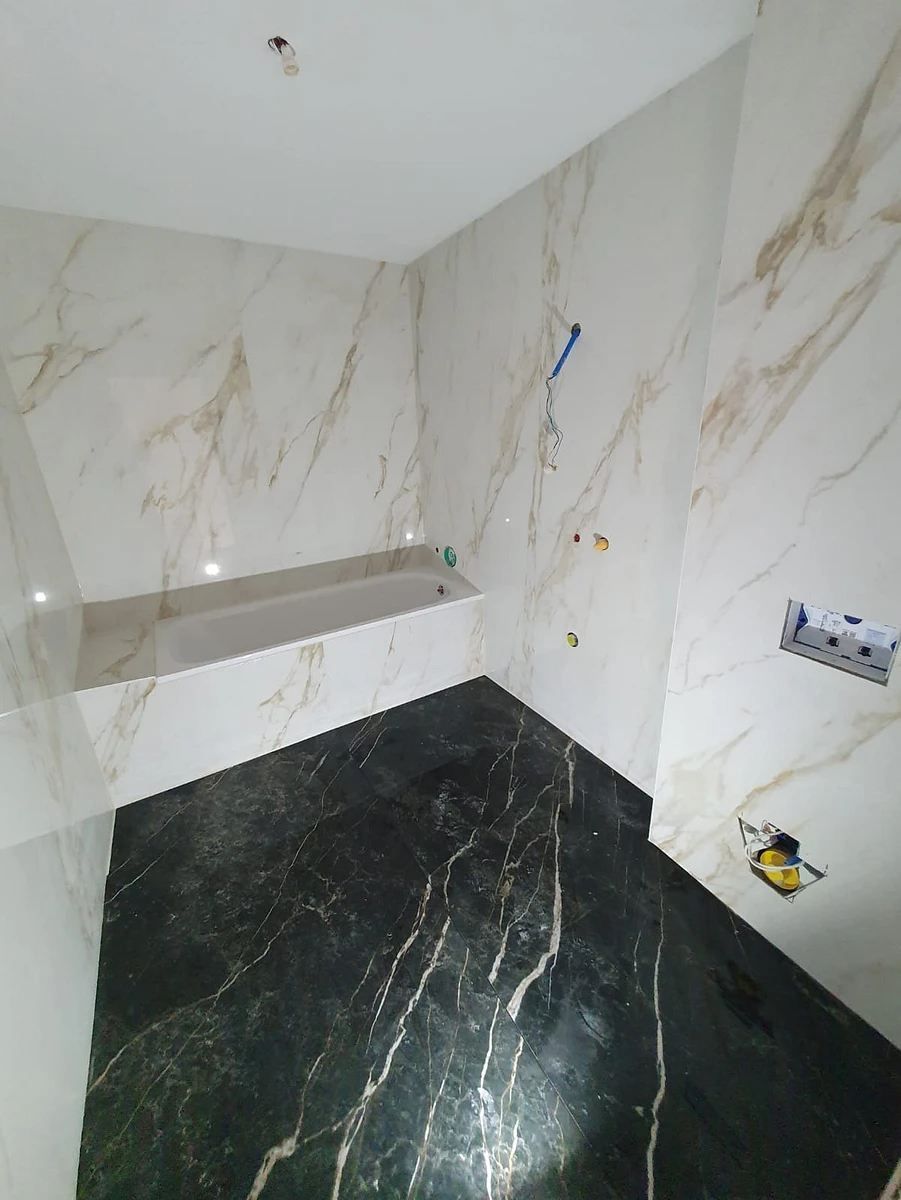 Une salle de bain avec des murs en marbre et un sol noir