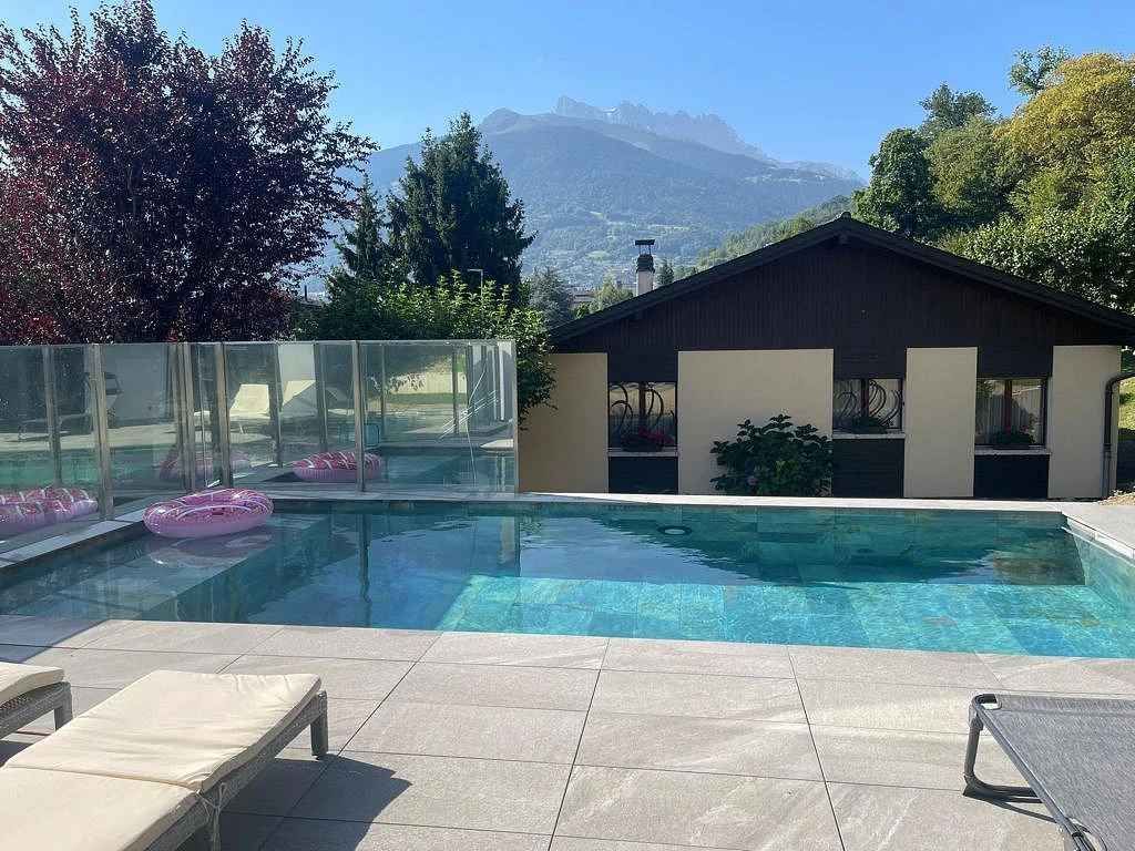 Une grande piscine devant une maison avec des montagnes en arrière-plan
