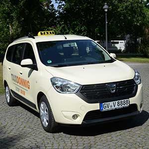 Ein weißes Taxi parkt auf einer Kopfsteinpflasterstraße.