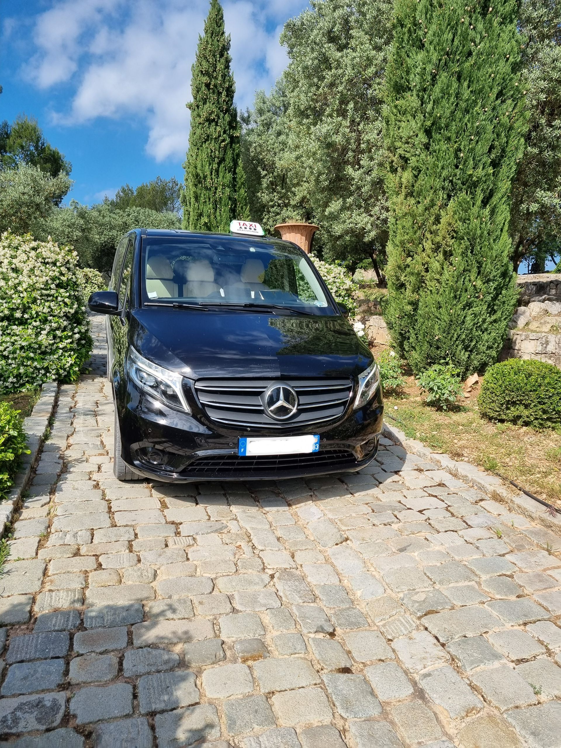 Taxi van Mercedes noir garé sur un chemin pavé