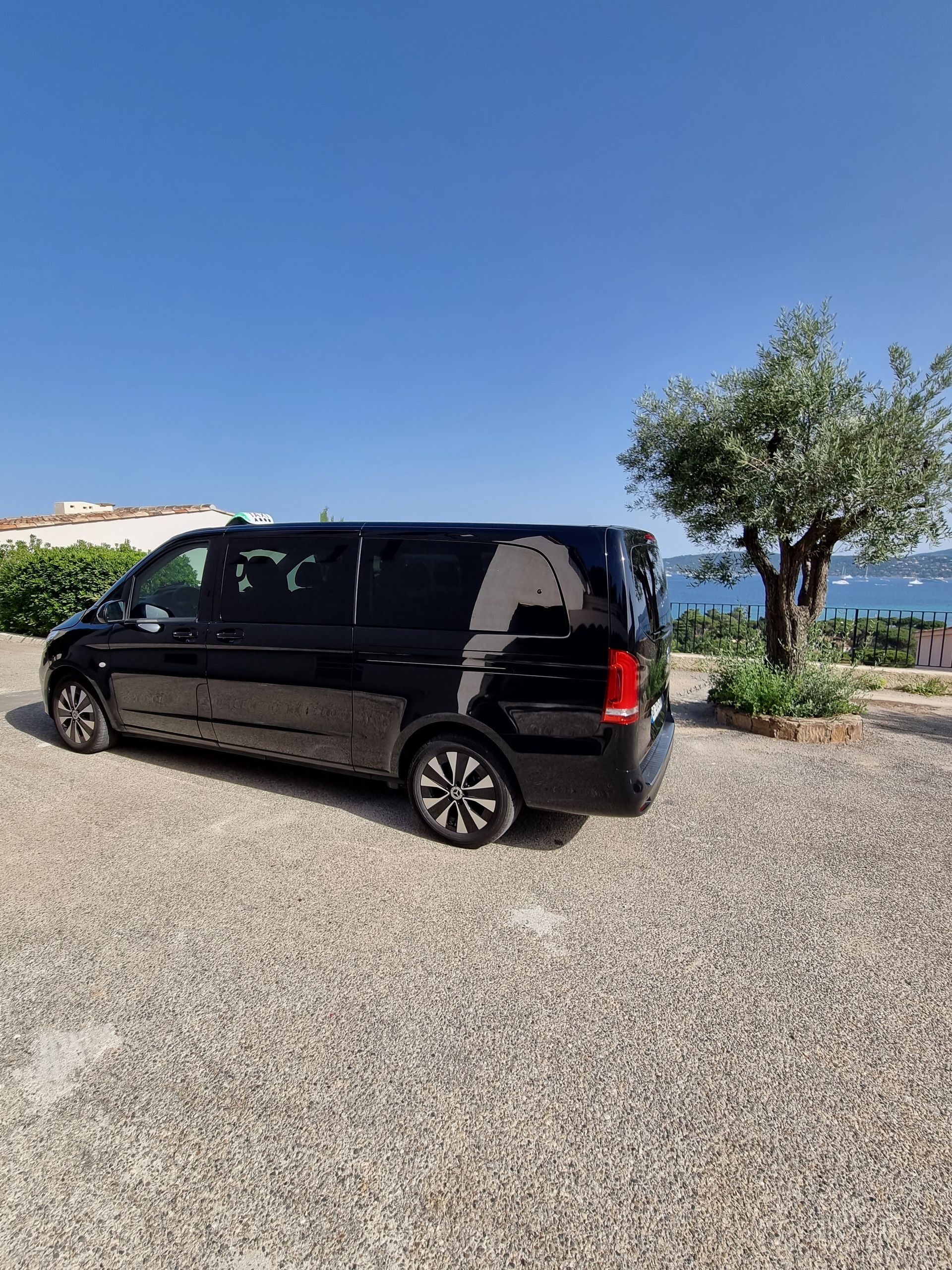 Van 8 places garé près d'un arbre et vu sur la Méditérranée