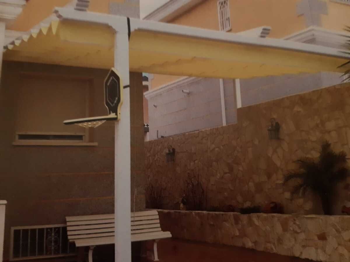 Un patio con un dosel y un banco debajo.