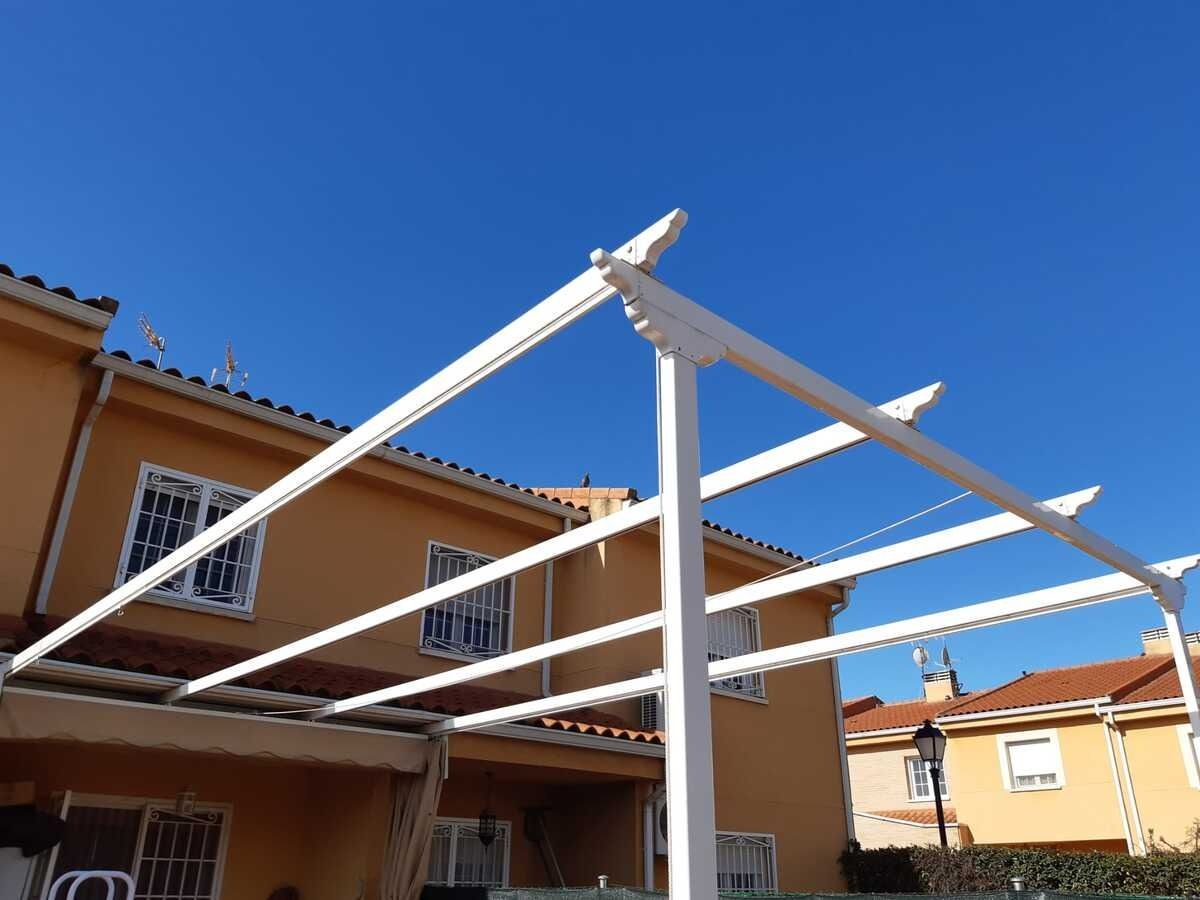 Se está construyendo una pérgola blanca delante de una casa.