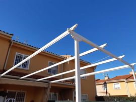 Se está construyendo una pérgola blanca delante de una casa.