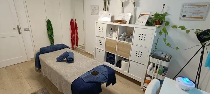 Sala de terapia de masajes con mesa de masajes, mueble de almacenaje y otros equipos.