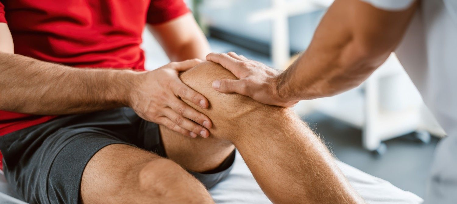 Otra persona examina la rodilla de una persona. Se le toca la rodilla, probablemente por razones médicas.