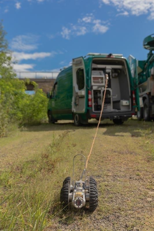 Ein grüner Lieferwagen parkt auf einem Feld neben einem kleinen Roboter.