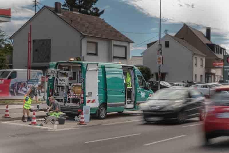 Ein grüner Lieferwagen steht am Straßenrand neben einem Haus.