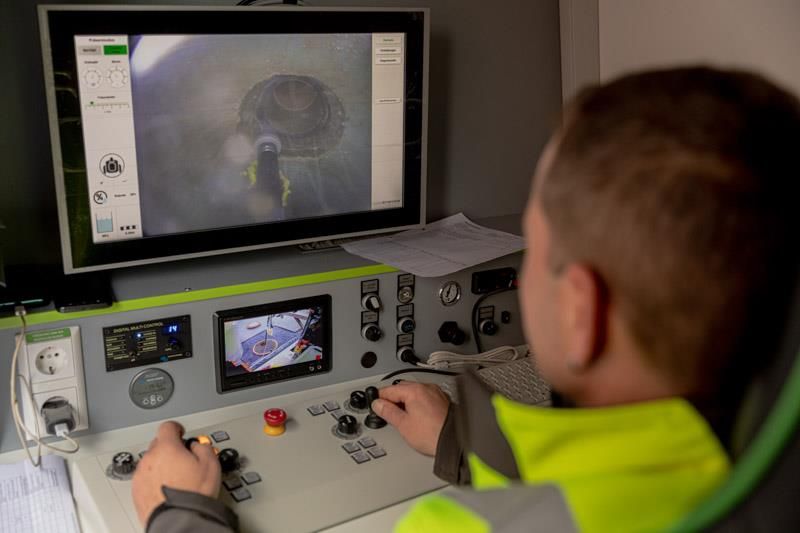 Ein Mann in einer gelben Jacke sitzt vor einem Computermonitor.