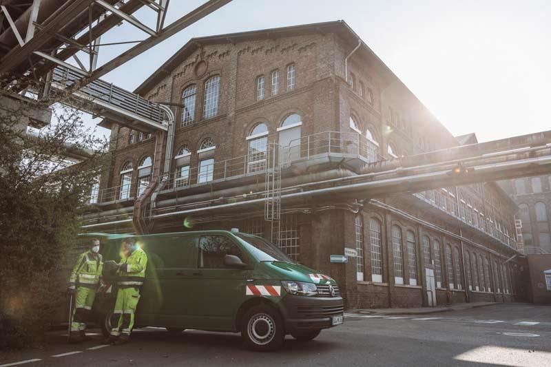 Ein grüner Lieferwagen steht vor einem Backsteingebäude.