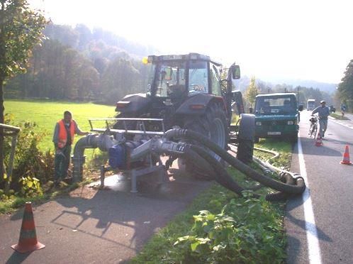 Ein Traktor mit einem daran befestigten Schlauch steht am Straßenrand