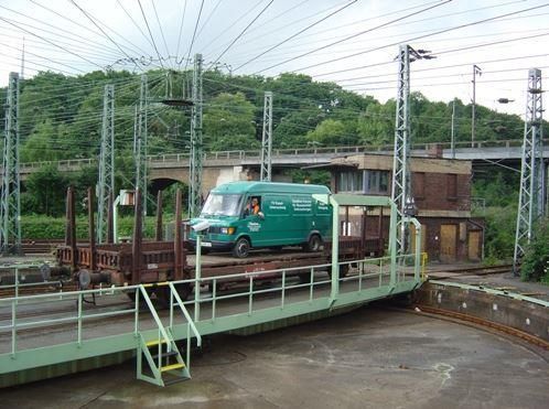 Ein grüner Lieferwagen fährt auf einem Bahngleis