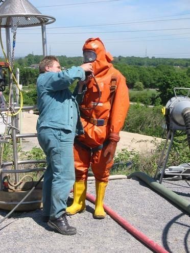 Ein Mann hilft einem anderen Mann, einen Schutzanzug anzuziehen