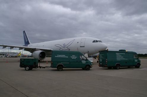 Ein Flugzeug wird von zwei grünen Transportern abgeschleppt.