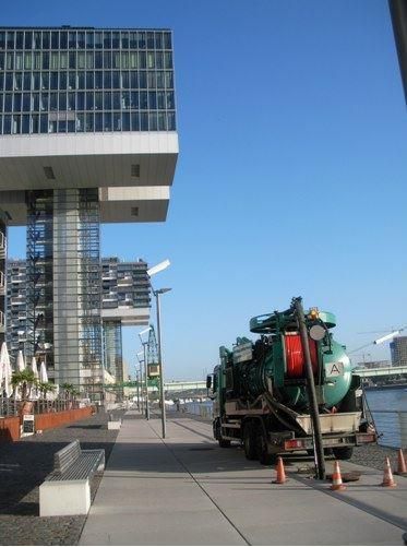 Ein grüner Saugwagen steht vor einem hohen Gebäude