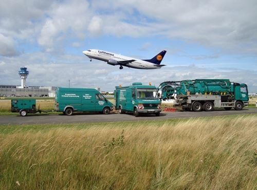 Ein Flugzeug fliegt über eine Reihe grüner Lastwagen